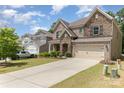 Suburban home exterior featuring a stone and brick facade, well-maintained lawn, and a paved driveway leading to a two-car garage at 5098 Burnwald Ct, Fort Mill, SC 29715