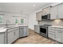 A view of the kitchen with stainless appliances, gray cabinets, and wood-look floors at 13022 Rover St, Charlotte, NC 28273