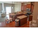 Open kitchen featuring stainless appliances, wood cabinets, granite countertops, and a central island at 14411 Glendon Hall Ln, Charlotte, NC 28262