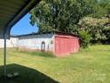 View of the property's red and white outbuilding with overgrown lawn at 408 Moose St, Albemarle, NC 28001