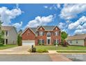 Inviting two-story brick home featuring a manicured lawn, garden beds, and a spacious driveway at 7800 Conifer Cir, Indian Trail, NC 28079