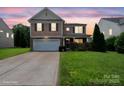 Beautiful two-story home with manicured lawn at sunset, stone accents, and an attached two-car garage at 8915 Merrie Rose Ave, Charlotte, NC 28213