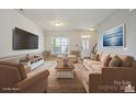 Inviting living room with neutral paint, light carpet, plenty of seating, and a mounted flatscreen television at 8915 Merrie Rose Ave, Charlotte, NC 28213