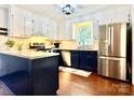 Modern kitchen with stainless steel appliances, white cabinets, and contrasting dark blue base cabinets at 9305 Harps Mill Ct, Charlotte, NC 28270