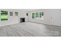 Bright living room featuring new gray flooring, a fireplace, and large windows at 1017 W Fisher St, Salisbury, NC 28144