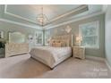 Serene main bedroom featuring a tray ceiling, soft lighting, and neutral decor for a relaxing retreat at 11313 Limehurst Pl, Charlotte, NC 28278