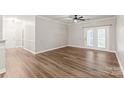 Bright, empty living room with wood-look flooring, ceiling fan, and double doors to balcony at 16344 Redstone Mountain Ln, Charlotte, NC 28277