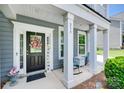 Inviting front porch featuring classic columns, rocking chair, and a decorative wreath on the front door at 230 Yale Pl, Fort Mill, SC 29707