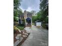 Charming two-story home with blue siding, stone chimney, and detached garage, nestled among mature trees at 27092 Village Dr, Fort Mill, SC 29708