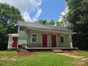 Green home featuring a covered porch and two red doors at 424 Congress S St, York, SC 29745
