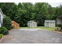 View of a spacious backyard with two storage sheds and gravel driveway at 6213 Golden Oak Ln, Denver, NC 28037