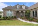 Inviting brick home entrance with manicured garden, columns, and a decorative door wreath at 82120 Standing Oak Dr, Charlotte, NC 28278