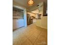 Bright kitchen with stainless steel appliances, tile flooring, white cabinetry and adjacent laundry area at 9125 N Vicksburg Park Ct, Charlotte, NC 28210