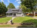 Beautiful single-Gathering home featuring a metal roof, covered front porch with swing, and a lush green lawn at 1025 Old Us 80 Hwy, Gold Hill, NC 28071