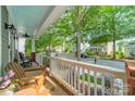 View of the tree lined street from the front porch with rocking chairs and a painted blue ceiling at 14533 Holly Springs Dr, Huntersville, NC 28078