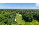 Stunning aerial view of a lush golf course surrounded by mature trees, providing a serene and picturesque landscape at 15811 Burlingame Dr, Huntersville, NC 28078