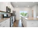 Modern kitchen features white cabinets, stainless appliances, granite countertops and access to outdoor deck at 7012 Bryce Ave, Charlotte, NC 28217
