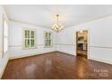 Spacious dining area with hardwood floors, shuttered windows, and an elegant chandelier leading into the well lit kitchen at 805 S Main St, Mount Holly, NC 28120