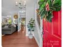 Bright foyer with a red door, hardwood floors, and view into the living room at 8700 Fox Tail Ln, Huntersville, NC 28078
