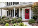 Inviting front porch with rocking chairs, a bright red door, and lush landscaping at 8700 Fox Tail Ln, Huntersville, NC 28078