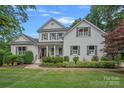 Charming white brick home featuring a manicured lawn, mature trees, and a welcoming front porch at 109 Walking Horse Trl, Davidson, NC 28036