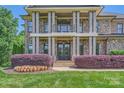A detailed view of the home's entrance, highlighting the stone facade, columns, and landscaped flowerbeds at 14041 Mccord Rd, Huntersville, NC 28078