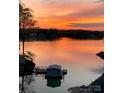 Serene lake view at sunset, casting a warm, orange glow over the waters and boathouse at 14608 Waterside Dr, Charlotte, NC 28278