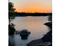 Stunning lake view with a brilliant orange sunset, highlighting the calm waters and boathouse at 14608 Waterside Dr, Charlotte, NC 28278