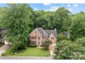 Lovely aerial view of a charming brick two-story home surrounded by mature trees at 17433 Glassfield Dr, Huntersville, NC 28078