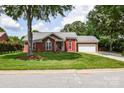 Charming brick home featuring red shutters, a well-manicured lawn, and a two-car garage at 4320 Atkinson Way, Monroe, NC 28110