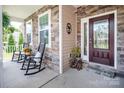 Inviting front porch with rocking chairs, stone accents, and a decorative front door at 512 Rosebush Ln, Clover, SC 29710
