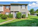 Inviting townhouse with lush green lawn, decorative shrubs, and covered entryway at 6044 Heath Valley Rd, Charlotte, NC 28210