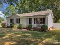 Inviting single-story home with manicured bushes, dark shutters, and a cozy front porch bench at 713 Springfield Nw Dr, Concord, NC 28027