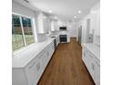 Modern eat-in kitchen with white cabinets, stainless steel appliances, hardwood flooring, and a large window at 7134 Rollingridge Dr, Charlotte, NC 28211