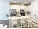 Well-lit kitchen featuring white cabinets, stainless steel appliances, quartz countertops and eat-in breakfast bar at 8060 Scarlet Maple Ln, Tega Cay, SC 29708