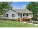 Traditional home with a cozy front porch, complemented by a lush green lawn and mature landscaping at 8593 Bailey Dr, Terrell, NC 28682