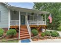 Close up of a charming covered front porch featuring a decorative door and well maintained landscaping at 8593 Bailey Dr, Terrell, NC 28682