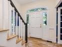 Bright foyer with hardwood floors, a white staircase, and a front door with arched glass at 9622 Penshurst Trce, Charlotte, NC 28210