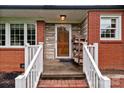 Inviting front porch with brick and stone accents, complemented by a wooden front door and white railings at 10637 Highway 52 Hwy, Rockwell, NC 28138