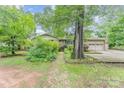 Traditional tan brick home with mature landscaping, grassy yard, and long concrete driveway at 203 Ewing Dr, Belmont, NC 28012