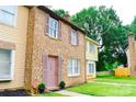 Brick townhome showcasing its charming side profile with a well-kept lawn and pink shutter accents at 7526 Holly Grove Ct, Charlotte, NC 28227