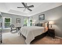 Calm main bedroom featuring a tray ceiling, fan, and natural light from the surrounding windows at 9009 Salford Ct, Huntersville, NC 28078