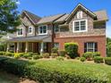 Charming two-story home featuring brick and stone accents, a covered porch, and mature landscaping at 126 Northbridge Dr, Mooresville, NC 28115