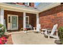 Inviting front porch features a cozy bench, white Adirondack chairs, and a brick exterior at 1624 Moonstone Dr, Matthews, NC 28105