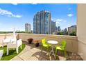 A sunny balcony with bright green chairs and cityscape views in the background on a partly cloudy day at 715 N Church St # 513, Charlotte, NC 28202