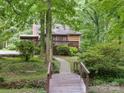 Back of the home featuring a deck, screened-in porch, and a bridge leading to the grassy backyard at 715 White Oaks Cir, Monroe, NC 28110