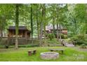 View of the home and guest house from the backyard with a bridge, fire pit, and benches at 715 White Oaks Cir, Monroe, NC 28110
