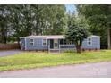 Charming single-story home with blue siding, a metal roof, and a well-manicured lawn surrounded by mature trees at 870 Family Dr, Midland, NC 28107