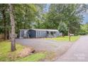 This lovely single-story home features new gravel, well-kept lawn, and a charming covered front porch, with mature trees surrounding the house at 870 Family Dr, Midland, NC 28107