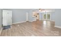 Open-concept living room with light blue walls, neutral vinyl floors and seamlessly flowing into the kitchen area with double doors to backyard at 870 Family Dr, Midland, NC 28107